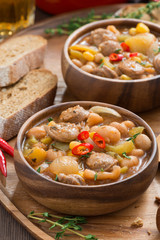 vegetable stew with sausages in a wooden bowl, vertical