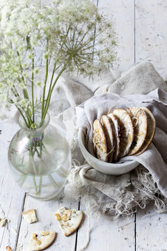 homemade cookies on bowl on white wooden table with wildflowers