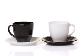 Black cup on the white plate and white cup on the black plate.