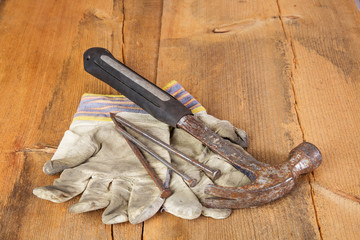 Rusty hammer, gloves and nails on wooden table