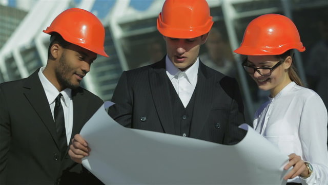 Three confident business architect in protective helmet standing