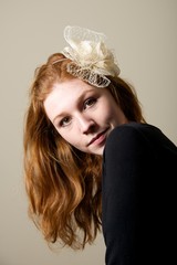 Redhead in cream fascinator looking over shoulder