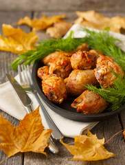 baked chicken drumsticks and fresh dill on a wooden background