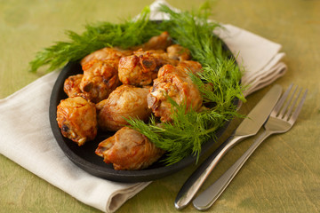 baked chicken drumsticks and fresh dill on a wooden background