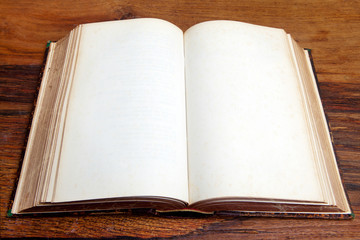 Open old book with blank pages on vintage wooden table. 