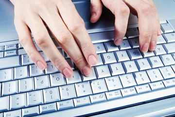 Silver keyboard and female hands. Working on a computer