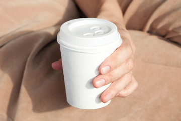 Young woman drinking coffee from disposable cup