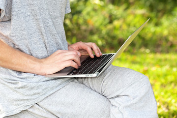 Man working in the park with a laptop. self employment, social distancing and remote work concept  