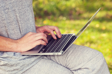 Man working in the park with a laptop. self employment, social distancing and remote work concept  