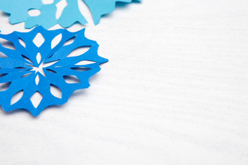 Abstract Christmas Background for your design. Blue paper cut snowflakes on white wooden background 
