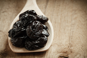 dried plums prunes on wooden spoon
