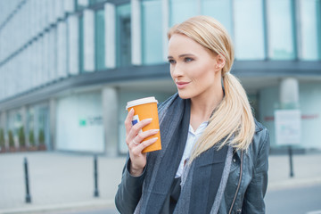 Attractive blond woman standing drinking coffee