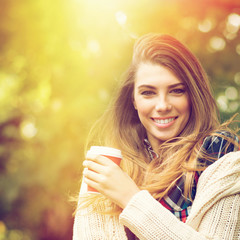 Cute young blonde girl with takeaway coffee in autum in park © BigLike Images