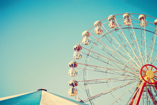 Vintage ferris wheel and tent over blue sky