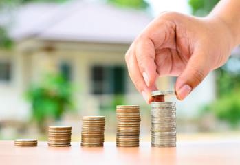 Male hand putting money coins stack like growing graph with home