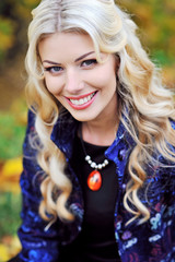 Beautiful elegant smiling woman standing in a park in autumn