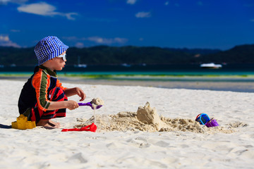 child building sandcastle on the beach