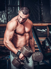 Muscular bodybuilder doing exercises with dumbbells