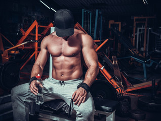 Fototapeta na wymiar muscle shaped man tired sitting relaxed with weights and energy