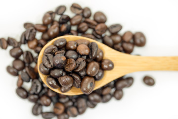 Coffee beans in a wooden spoon on white background