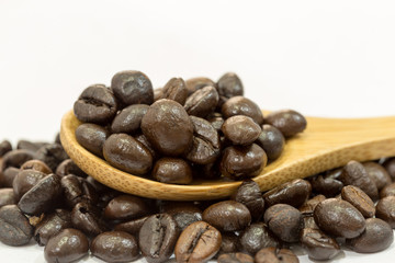 Coffee beans in a wooden spoon on white background