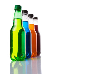 Multicolored soda drinks in bottles over white background