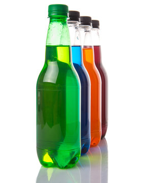 Multicolored soda drinks in bottles over white background