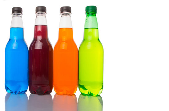 Multicolored soda drinks in bottles over white background