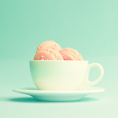 Pink macaroons in a white tea cup
