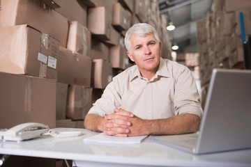 Warehouse manager with laptop at desk