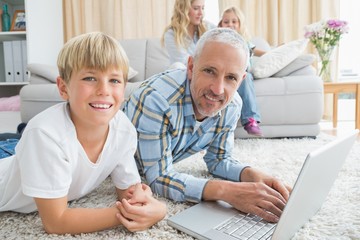 Obraz premium Father and son using laptop on the floor