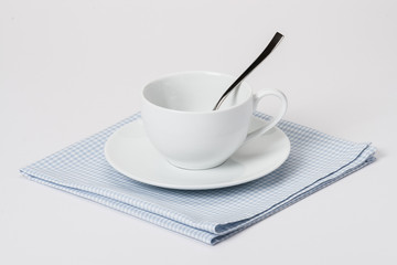 Cup, Plate And Spoon On Folded Gingham Cotton Napkin. White Back