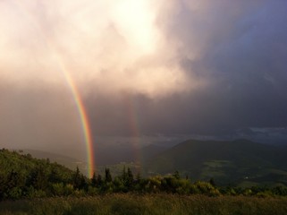Fototapeta na wymiar Regenbogen vor Bergpanorama
