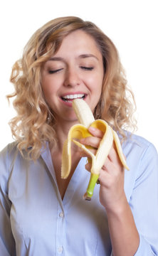 Frau mit blonden Locken geniesst eine Banane