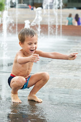 Happy kid playing in a fountain
