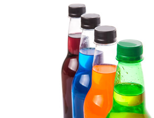 Multicolored soda drinks in bottles over white background