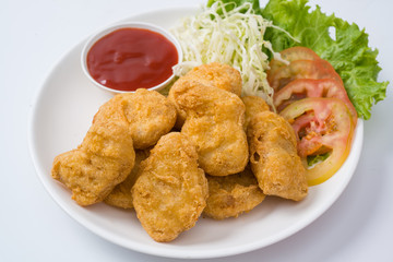 Chicken nuggets on a plate with sauce and vegetables on the plat