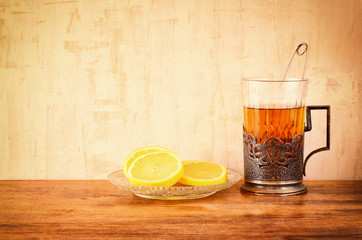 vintage tea glass-holder with fresh lemons over wooden table. re
