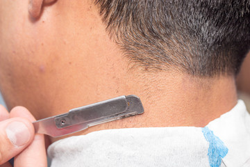Hairdresser shaving man's neck with a straight razor