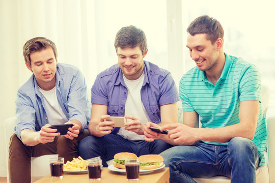 Smiling Friends Taking Picture Of Food At Home