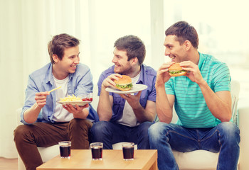 smiling friends with soda and hamburgers at home