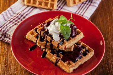Waffles with chocolate sauce, whipped cream and confiture