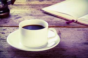 Cup of black coffee with a book