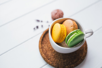 Coloured macarons in cup on white with shallow depth of field