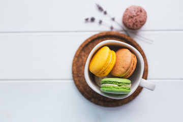Coloured macarons in cup on white with shallow depth of field