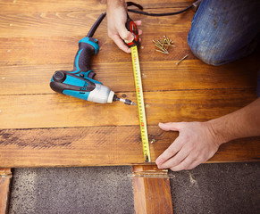 Male hands measuring wooden floor