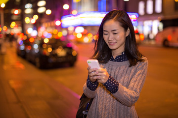 Young Asian Woman texting cellphone at night
