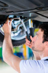 KFZ-Mechaniker arbeitet in Autowerkstatt