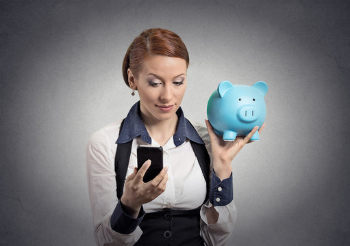 woman holding piggy bank looking at smart phone