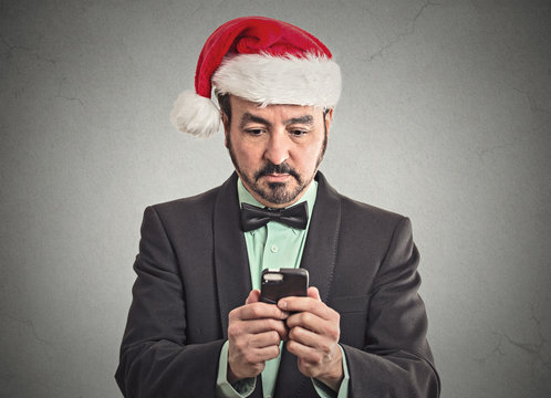 man in santa claus hat looking at smartphone online deal